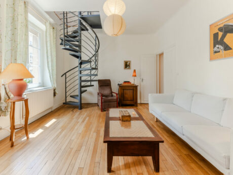 Salon avec escalier en colimaçon et canapé blanc.