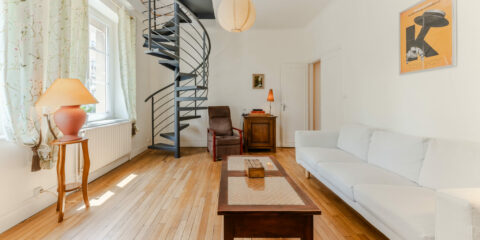 Salon avec escalier en colimaçon et canapé blanc.