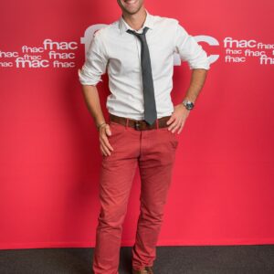 Homme souriant devant un fond rouge Fnac.