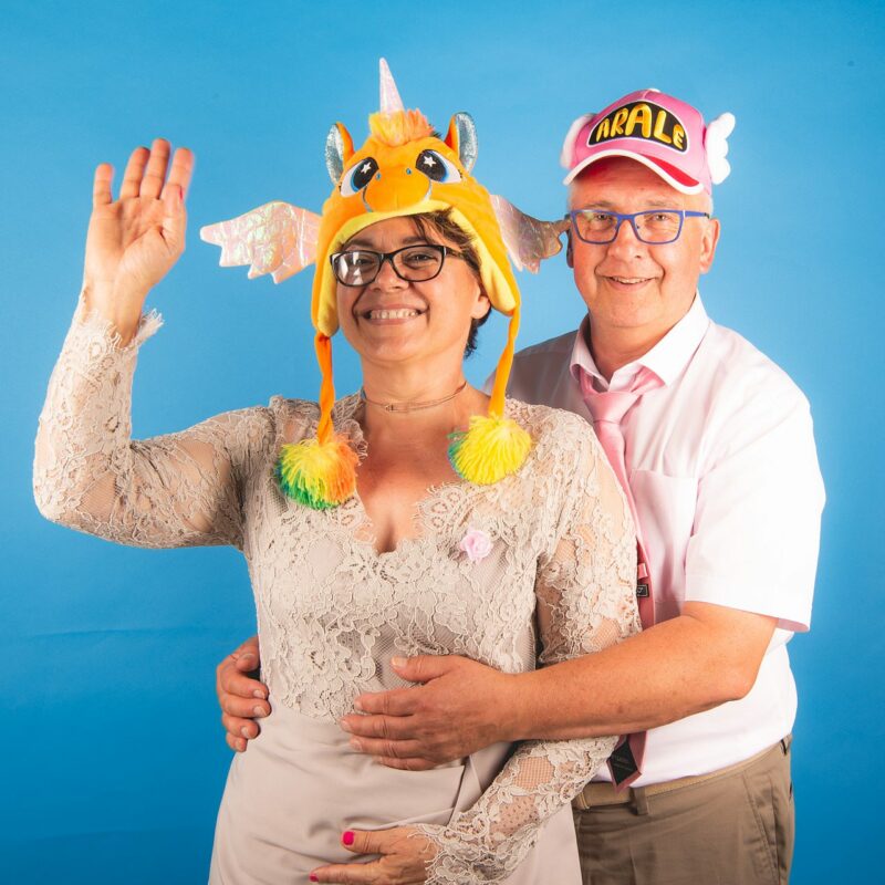 Deux personnes souriantes avec des chapeaux colorés.