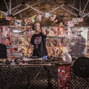 DJ souriant avec des couvertures vintage colorées.