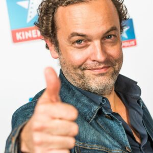 Homme souriant avec un pouce levé.