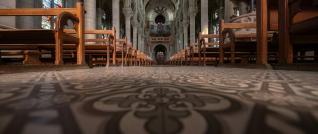 Intérieur d'église avec bancs et vitraux colorés.