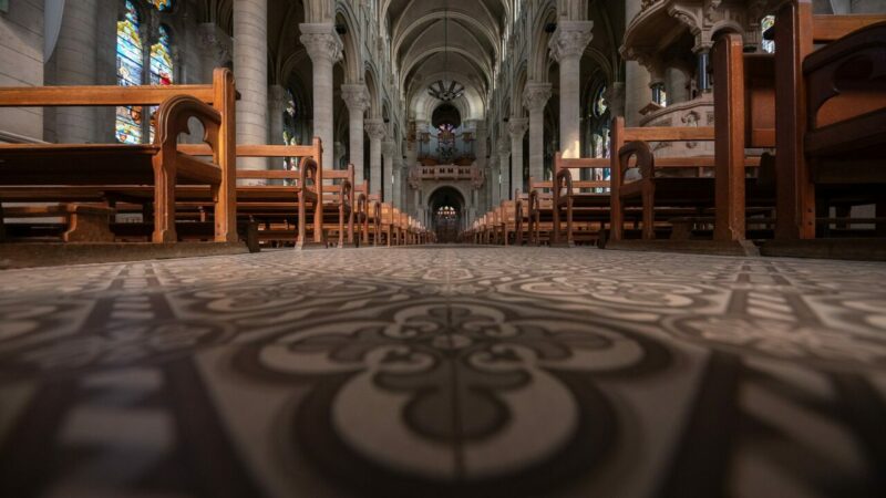 Intérieur d'église avec bancs et vitraux colorés.