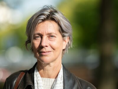 Femme souriante en extérieur, lumière naturelle.