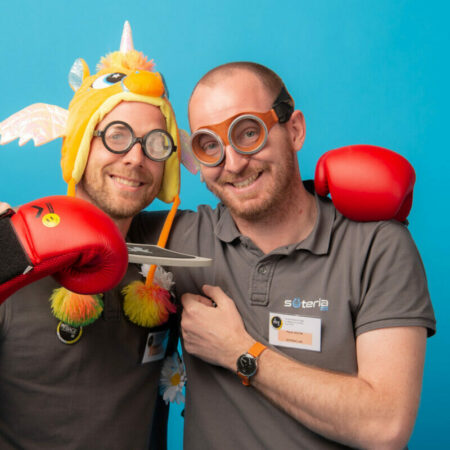 Deux hommes souriant avec déguisements et jouets.