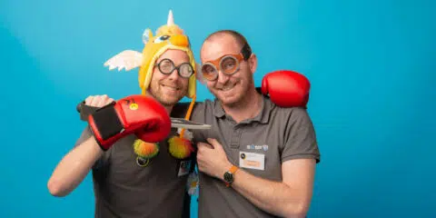 Deux hommes souriant avec déguisements et jouets.