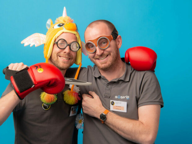 Deux hommes souriant avec déguisements et jouets.