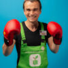 Homme souriant avec des gants de boxe rouges.