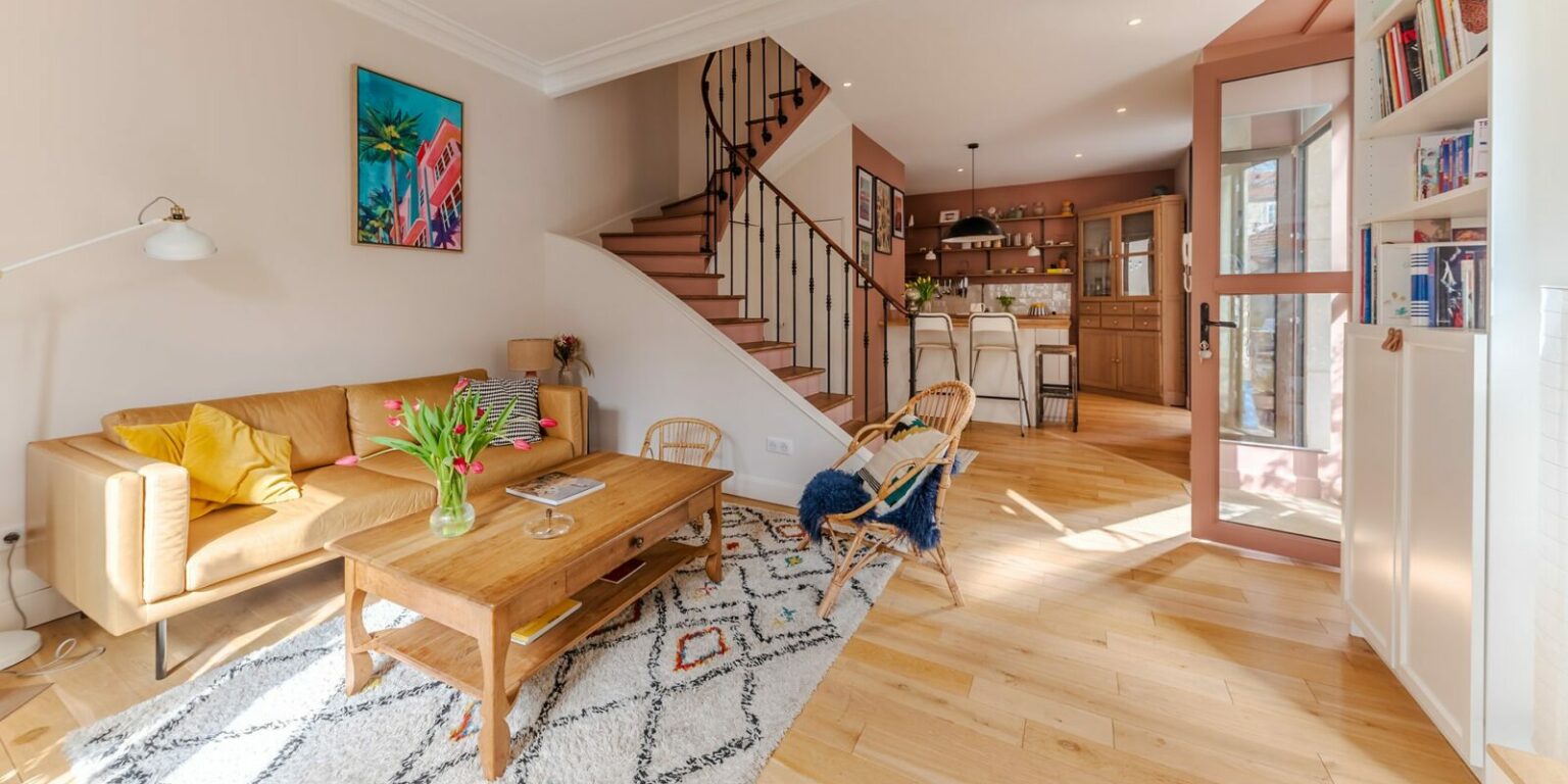 Salon lumineux avec escalier en bois.