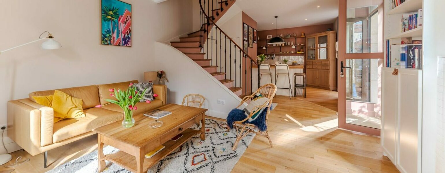 Salon lumineux avec escalier en bois.