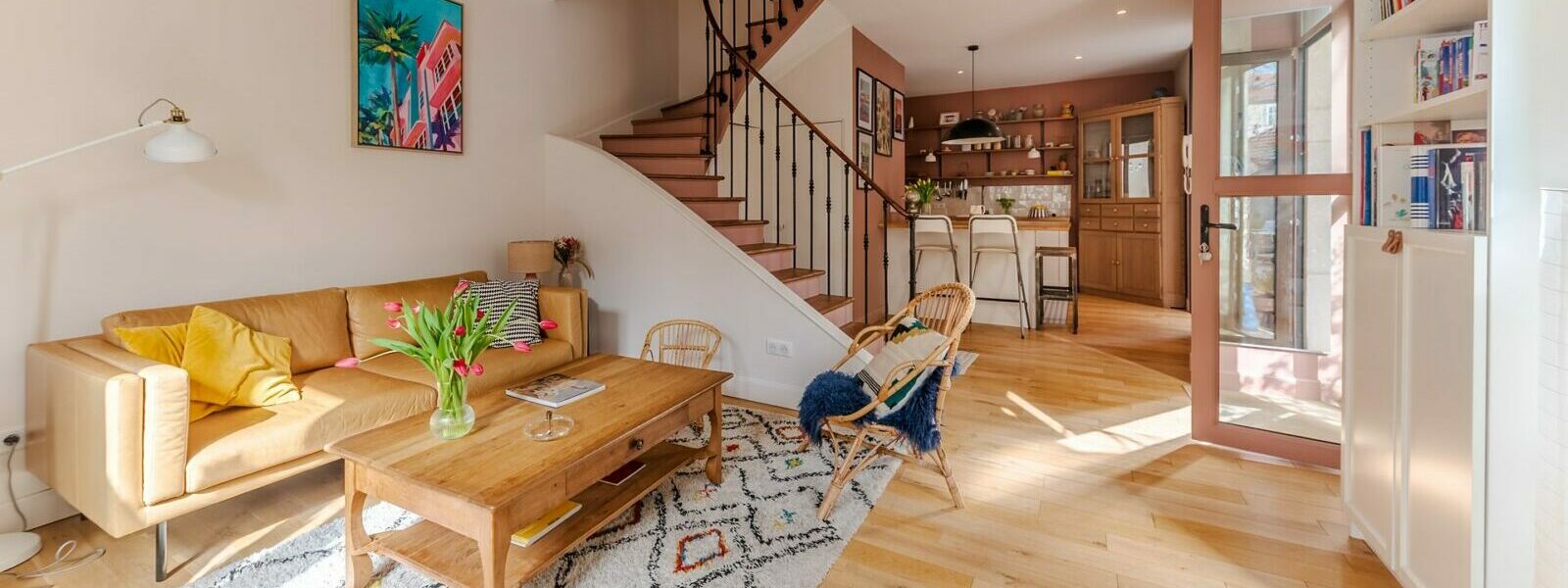 Salon lumineux avec escalier en bois.