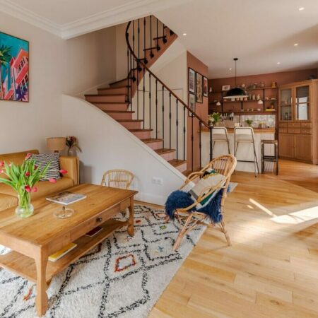 Salon lumineux avec escalier en bois.