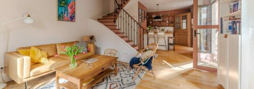 Salon lumineux avec escalier en bois.