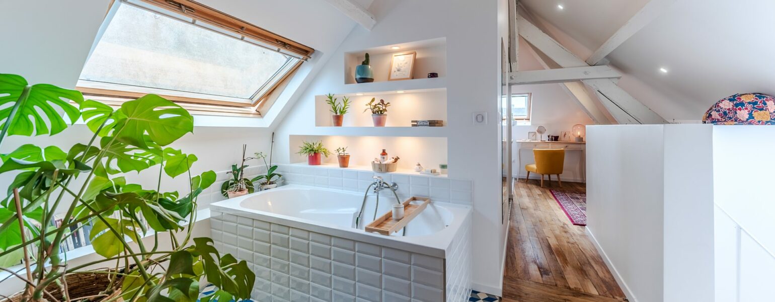 Salle de bain lumineuse avec plantes et baignoire.