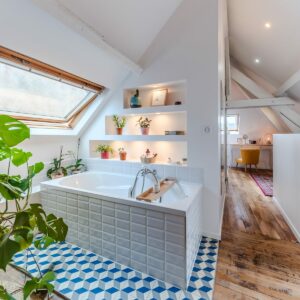 Salle de bain lumineuse avec plantes et baignoire.