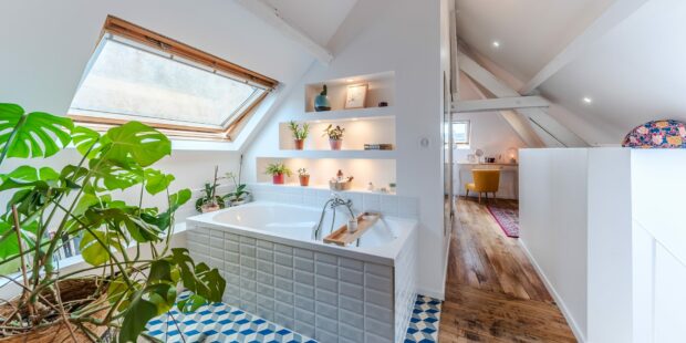 Salle de bain lumineuse avec plantes et baignoire.