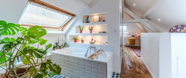 Salle de bain lumineuse avec plantes et baignoire.