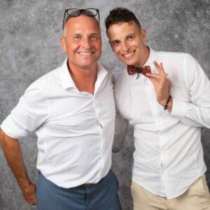 Deux hommes souriants en chemises blanches.