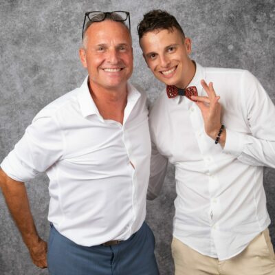 Deux hommes souriants en chemises blanches.