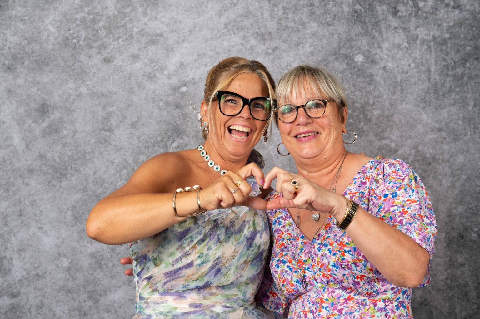 Deux femmes souriantes formant un cœur avec les mains.