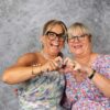 Deux femmes souriantes formant un cœur avec les mains.