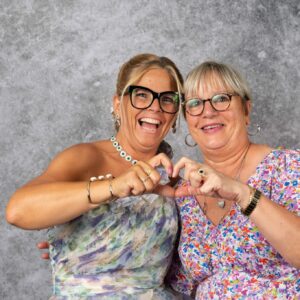 Deux femmes souriantes formant un cœur avec les mains.