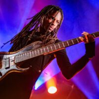 Personne jouant de la basse sur scène éclairée.