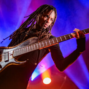 Personne jouant de la basse sur scène éclairée.