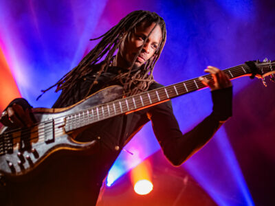 Personne jouant de la basse sur scène éclairée.