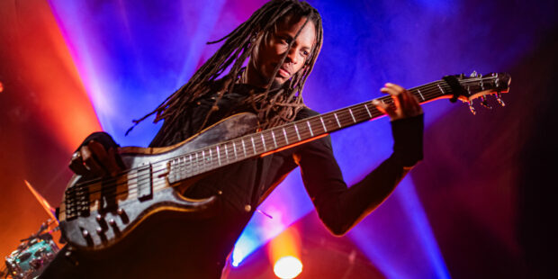 Personne jouant de la basse sur scène éclairée.