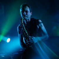 Musicien jouant du saxophone sur scène éclairée.