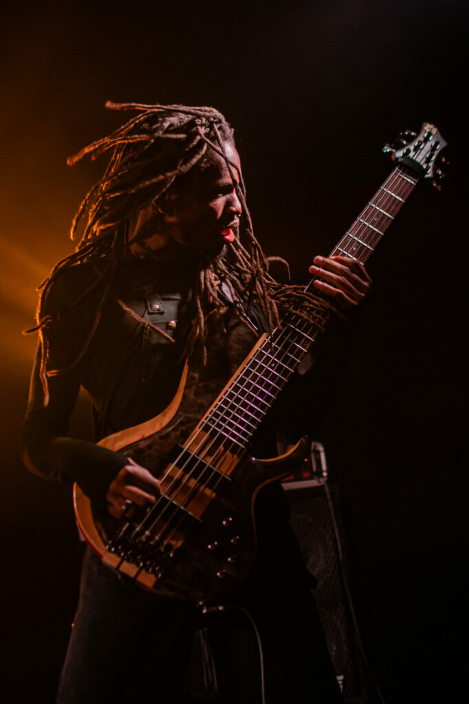 Musicien jouant de la guitare basse sur scène.