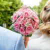 Couple marié tenant un bouquet de roses roses.