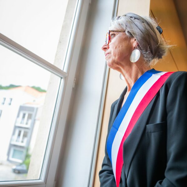 Femme regardant par la fenêtre avec écharpe tricolore.