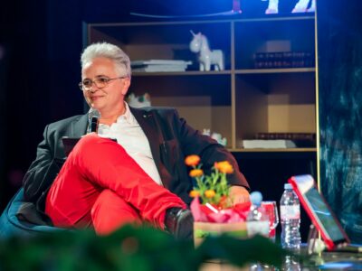 Personne assise avec microphone, décor lumineux.