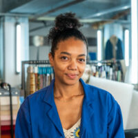 Femme souriante en blouse bleue dans un atelier.