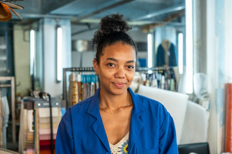 Femme souriante en blouse bleue dans un atelier.