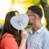 Couple cachant un baiser avec éventail cœur.