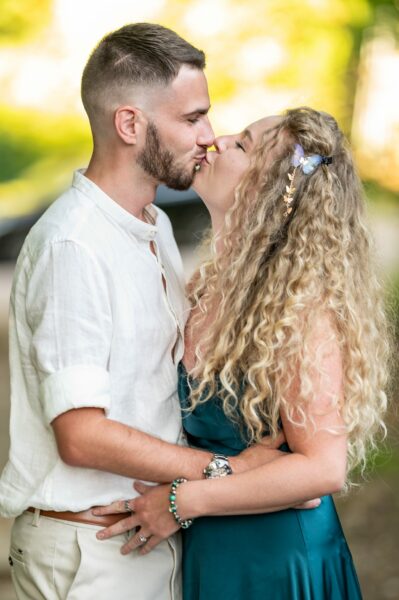 Couple s'embrassant tendrement dans un parc verdoyant.