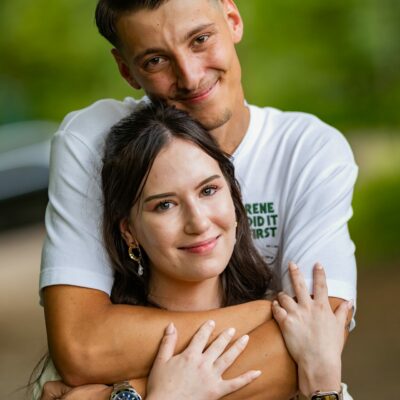 Couple s'enlaçant dans un parc verdoyant.