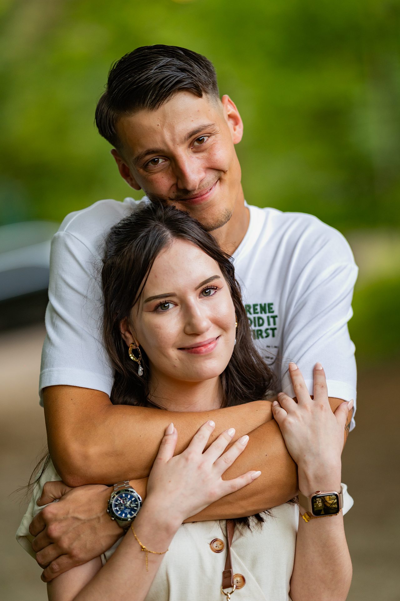 Couple s'enlaçant dans un parc verdoyant.