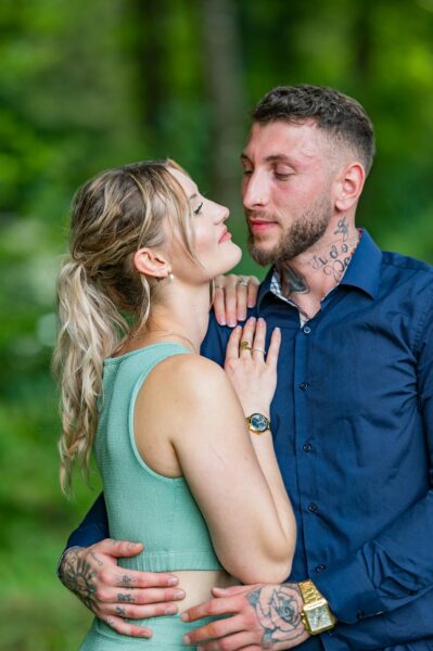 Couple s'enlaçant dans un parc verdoyant.