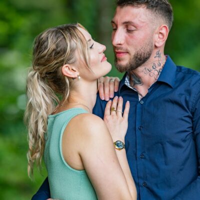 Couple s'enlaçant dans un parc verdoyant.