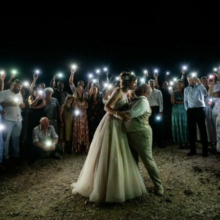 Mariage de nuit entouré d'invités avec téléphones illuminés.