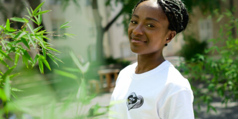 Personne souriante, fond verdoyant.