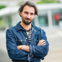 Homme en veste en jean croisant les bras.