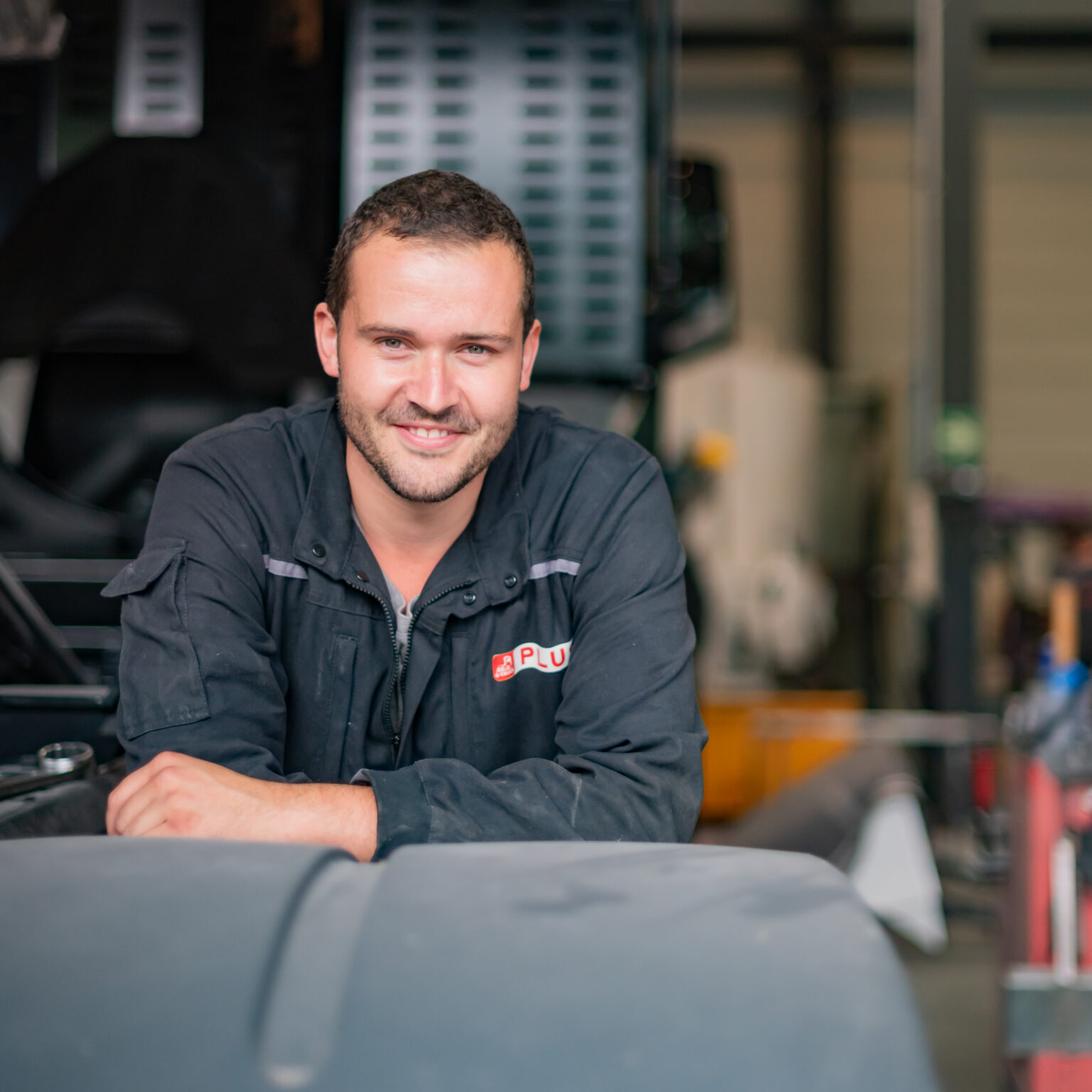 Homme souriant en tenue de travail dans un atelier.