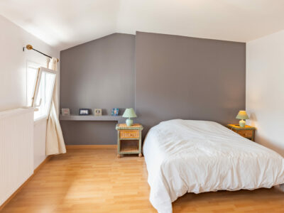 Chambre lumineuse avec lit double et murs gris.