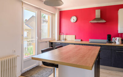 Cuisine moderne avec mur rouge et îlot central.